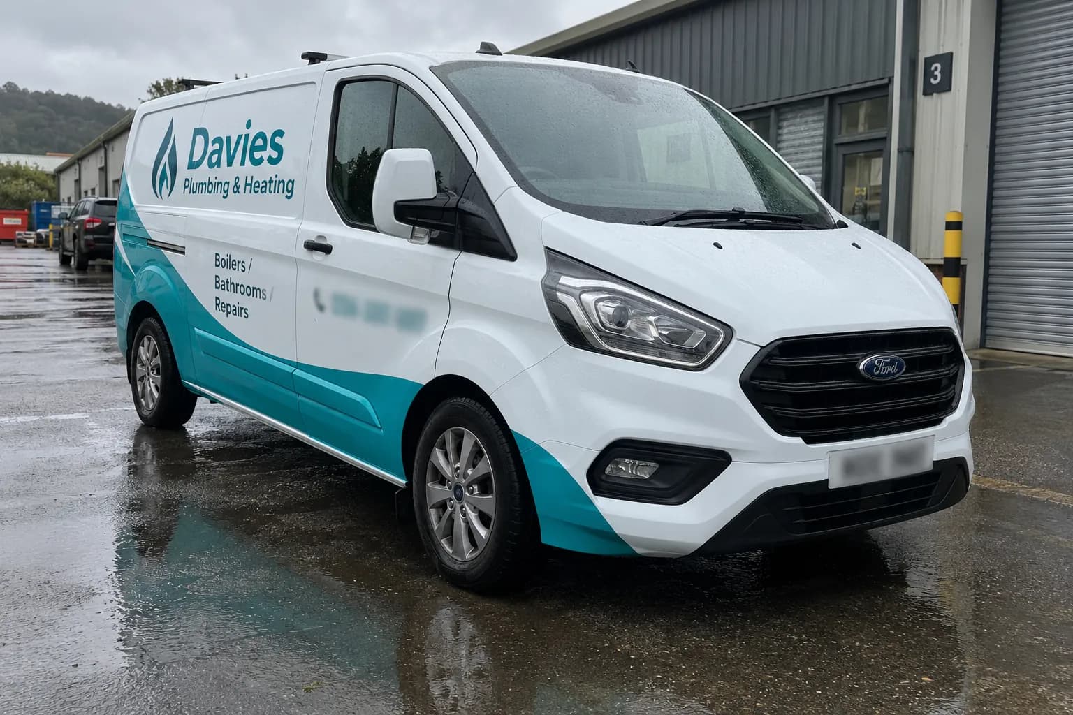 White Ford Transit with a teal part wrap and plumbing and heating lettering