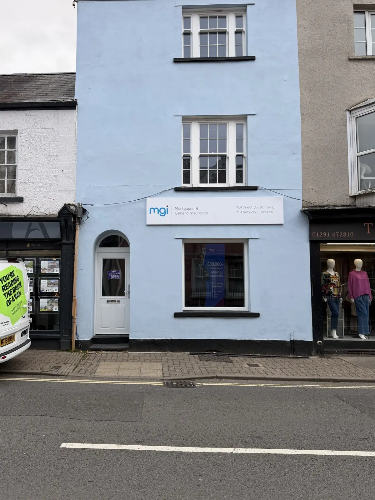 MGi Mortgages & General Insurance fascia sign above the window of a pale blue high-street office